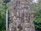 An ancient Khmer tower is decorated with four smiling stone faces