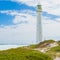 Ancient lighthouse on a grassy shore under a beautiful cloudy sky in Cape Town, South Africa