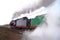 Ancient locomotive rides the railway. Steam railway machine in smoke