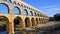 Ancient Majesty: Roman Aqueduct Gracefully Spanning Over Gentle River