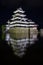 Ancient Matsumoto Castle at night with reflection in moat