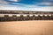 Ancient medieval fortress barrier wall on sandy beach as breakwater, in sunny blue sky with clouds, creative background design