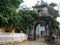 Ancient mossy village gate hidden in the shade of green trees