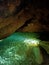 Ancient mountain cave with stalactites, stalagmites, long underground river in white and red stones with petroglyph