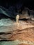 Ancient mountain cave with stalactites, stalagmites, long underground river in white and red stones with petroglyph