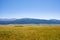 Ancient nomadic mound grave on green valley with mountains and blue sky