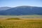 Ancient nomadic mound grave on green valley with mountains and blue sky