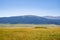 Ancient nomadic mound grave on green valley with mountains and blue sky