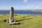 Ancient ogham stone monument on Dunmore Head in Dingle, Ireland, with blue sky in the background