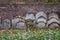 Ancient overgrown tombstones and graves placed relocated against brick wall at churchyard garden on autumn morning