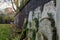 Ancient overgrown tombstones and graves placed relocated against brick wall at churchyard garden on autumn morning