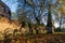 Ancient overgrown tombstones and graves placed relocated against brick wall at churchyard garden on autumn morning