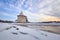 Ancient Pskov in winter. The Flat tower of the Pskov Kremlin against the blue sky. In the foreground, the river is