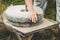 The ancient quern stone hand mill with grain. The man grinds the grain into flour with the help of a millstone. Men`s