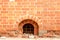 Ancient red brick wall with small cellar window with metal bars