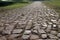 Ancient road paved with cobblestone and going up through hills.