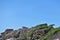 Ancient rocks against the sky. Smooth gray boulders are covered with green vegetation.