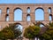 Ancient Roman aqueduct in Greece with orange trees in front of it