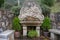 Ancient roman water source with symbols and benches. Roman heritage concept. Stone roman fountain outdoor.