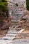 Ancient ruined partly broken stone stairs on rock leading up the hill surrounded by pine trees