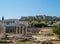 Ancient ruins of buildings and the remains of a colonnade in the Roman Agora with the Acropolis in the background in Athens,