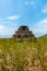 An ancient small pyramid shaped worship idol prayer place made of stones in the middle of a meadow with beautiful landscapes.