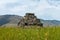 An ancient small pyramid shaped worship idol prayer place made of stones in the middle of a meadow with beautiful landscapes.