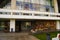 Ancient Soviet hotel facade with stone columns, panoramic windows, sloping roof, bench on the grassy lawn beside the entrance.