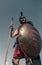 Ancient Spartan warrior in battle dress stands with shield and spear