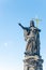 Ancient statue of a saint monk with a cross at the Charles Bridge in Prague at blue sky and copy space, Czech Republic, summer,