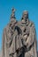 Ancient statue of two monks with Bible at the Charles Bridge in Prague at blue sky, Czech Republic, summer, closeup