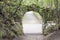 Ancient stone arch overgrown with moss. Path leading to stone wall opening horizontal