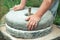 The ancient stone hand grain mill. Men`s hands rotate a stone millstone