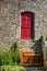 Ancient stone house with a wooden barrier and a red door