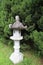 An ancient stone lantern stands among the cypress trees in the temple.