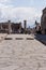 Ancient stone street with columns and statue and tourists in Pompeii, Italy. Antique culture concept. Pompeii ruins.