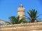 Ancient tower with palm trees and arabic writing and blue sky