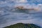 Ancient town Buzet with bell tower and flying above clouds.