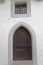 Ancient white wall with a brown door, close-up