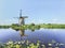 Ancient wind mill reflected in a blue canal on a summer day