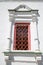 Ancient window with red bars decorated with columns umbrella roof