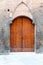 Ancient wooded double doors in a brick wall with decorative arch