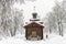 Ancient wooden church. Winter landscape. A worker removes the sn