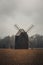 Ancient wooden mill standing alone in a field in gloomy foggy weather. Historical building for grinding corn, Opava, Czech