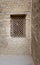 Ancient wooden window with geometrical pattern based on the christian cross on external brick stone wall