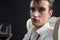 Androgynous man holding wine glass against black background