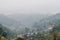 Andscape view of mist-covered village in the mountains in the background.