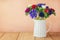 Anemone flowers in white vase on wooden table