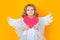 Angel child with heart. Cute angel child, studio portrait. Angel kid with angels wings, isolated background.