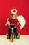 Angel little boy on red background on bike